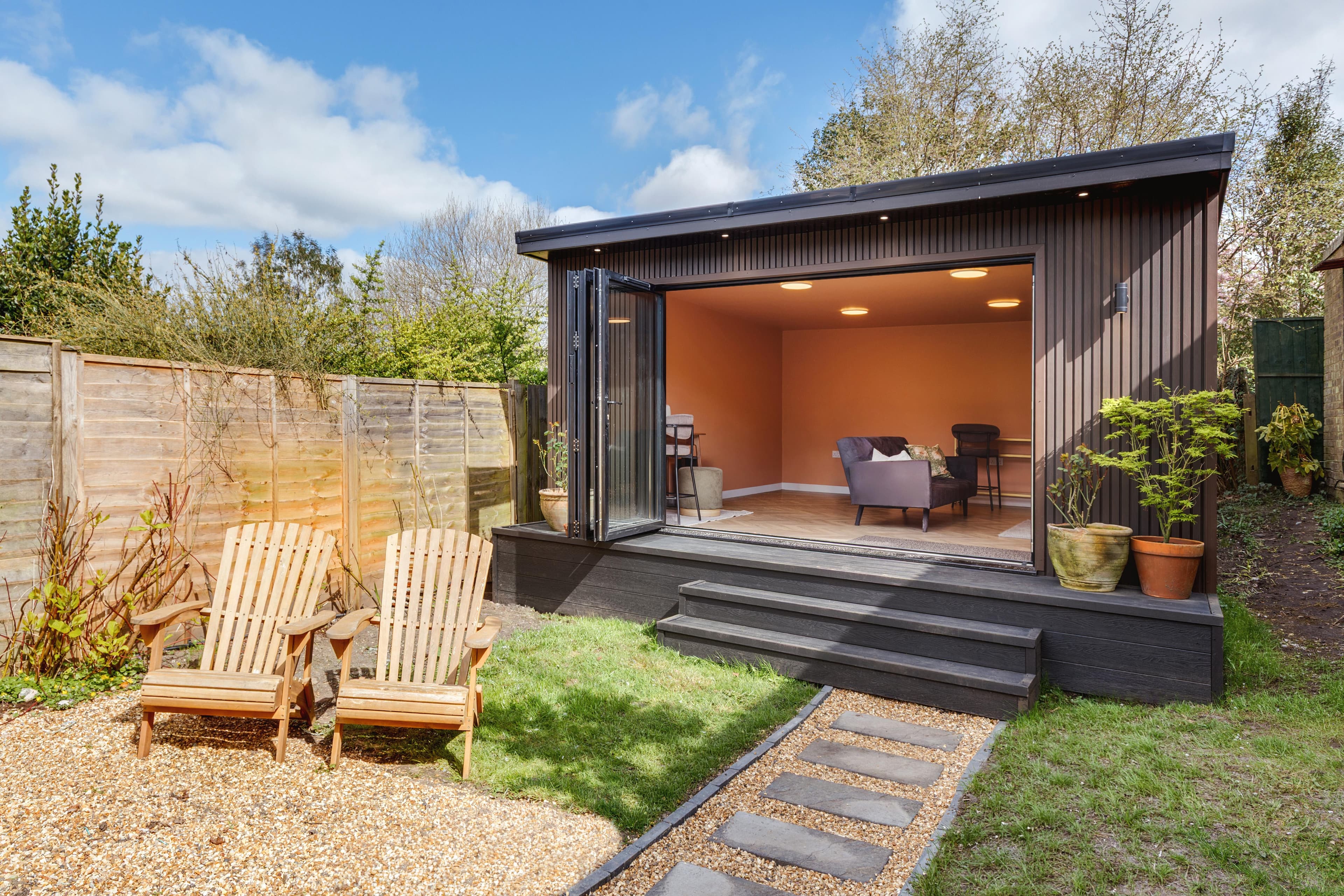 Black-clad garden annexe in Bedfordshire with a warm terracotta living space inside