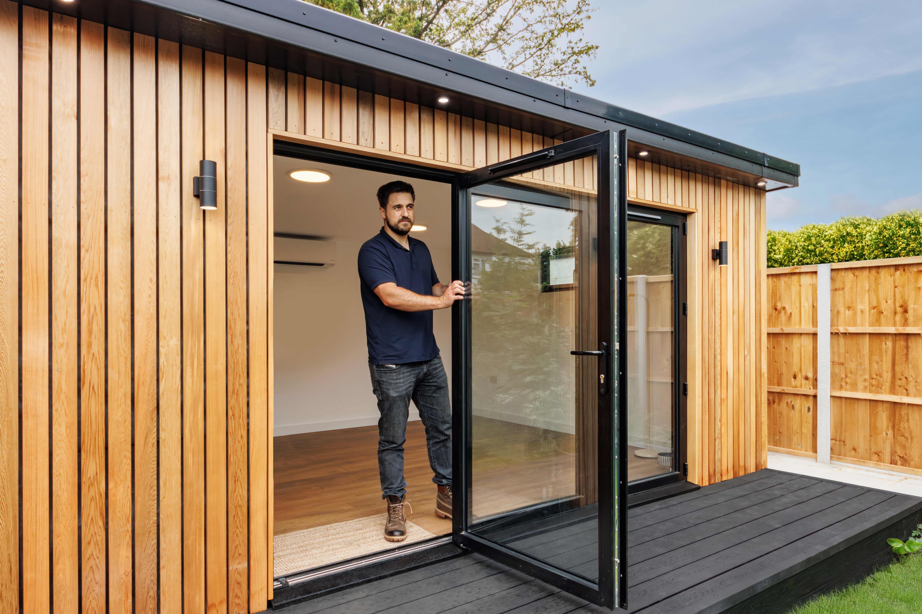 Cedar-clad garden office in Bedfordshire with black bifold doors open onto a deck