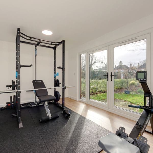 Garden gym in Bedfordshire with a power rack, weight bench and rowing machine