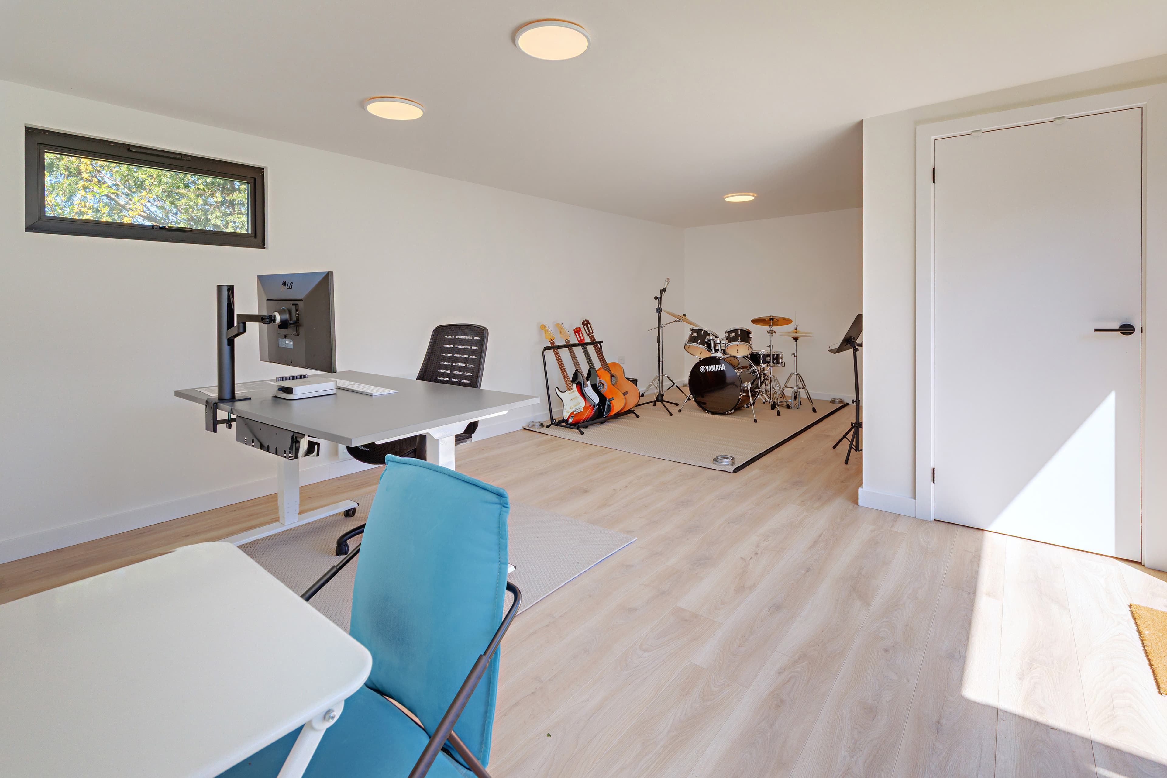 Garden music studio interior in Bedfordshire with a standing desk, guitars on a stand and a drum kit