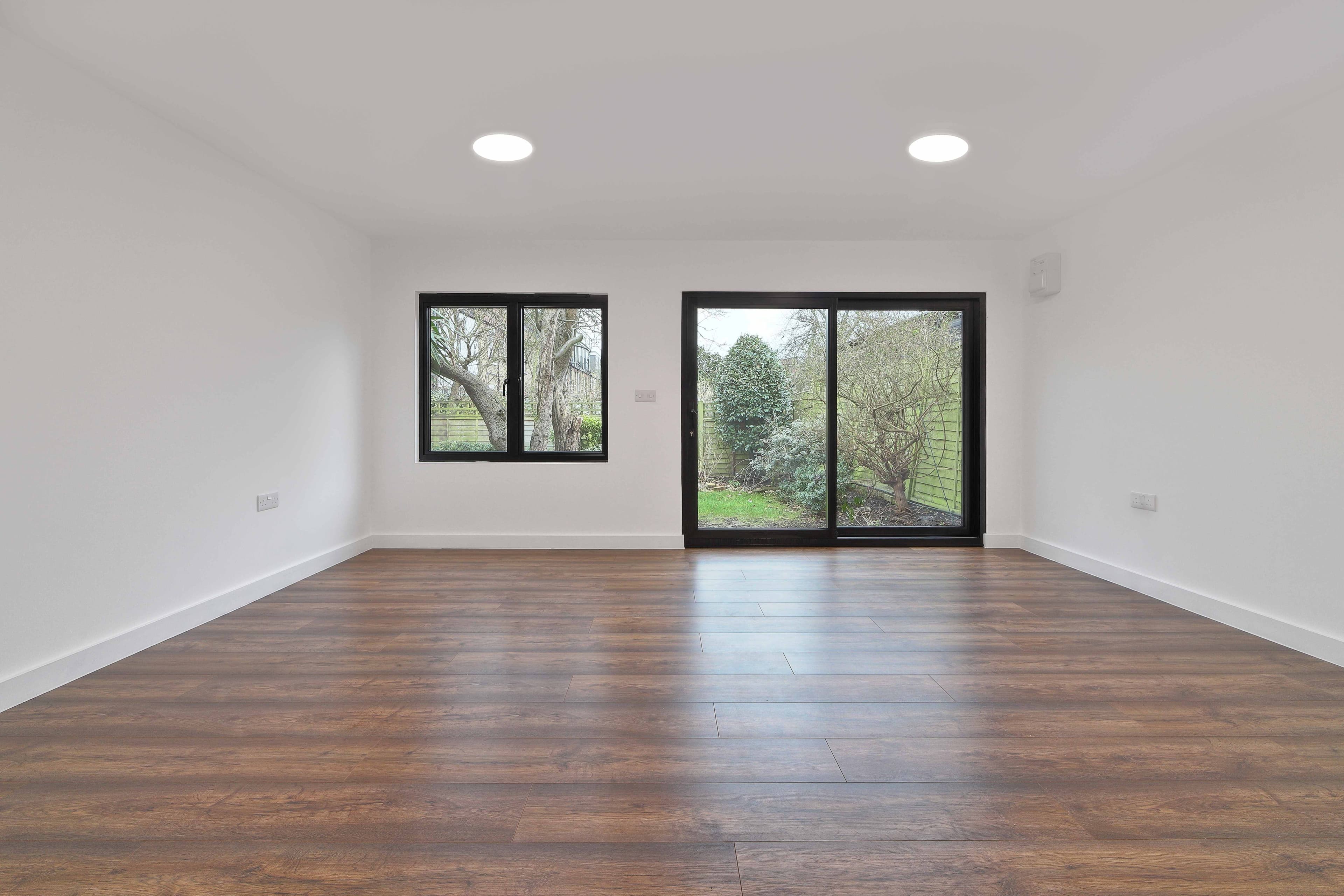 Garden room interior in Bedfordshire with dark wood flooring and black-framed sliding doors to the garden