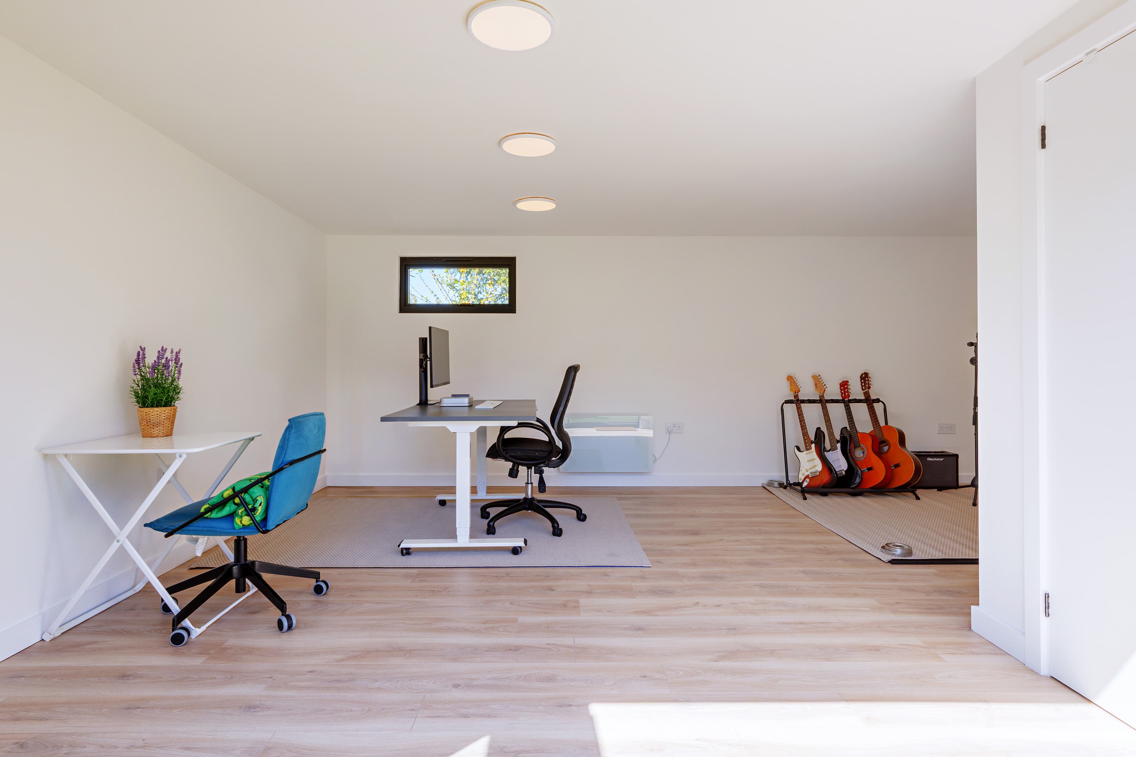 Bright garden studio in Bedfordshire set up with a desk, chairs and a pair of guitars