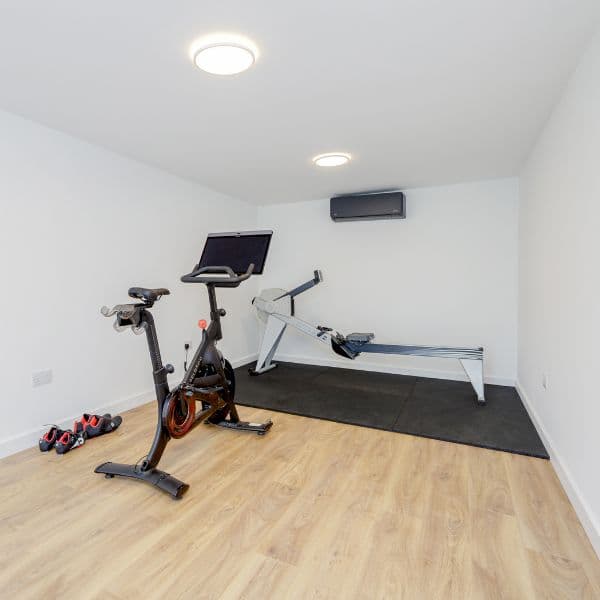 Garden gym in Cranfield — strength-training zone with a squat rack, bench and rubber gym flooring