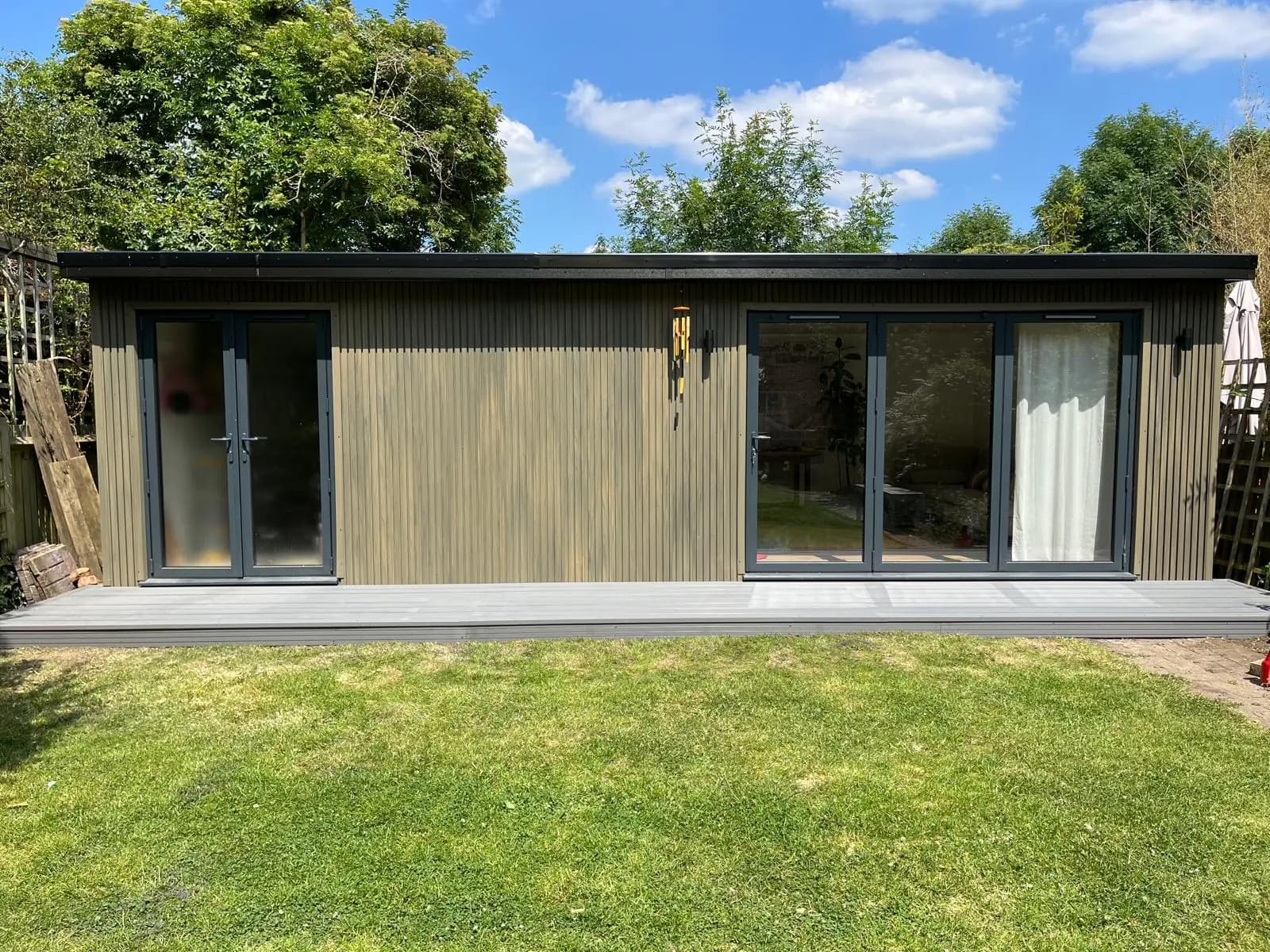 Long garden annexe with ribbed cladding, double doors and a wide glazed opening