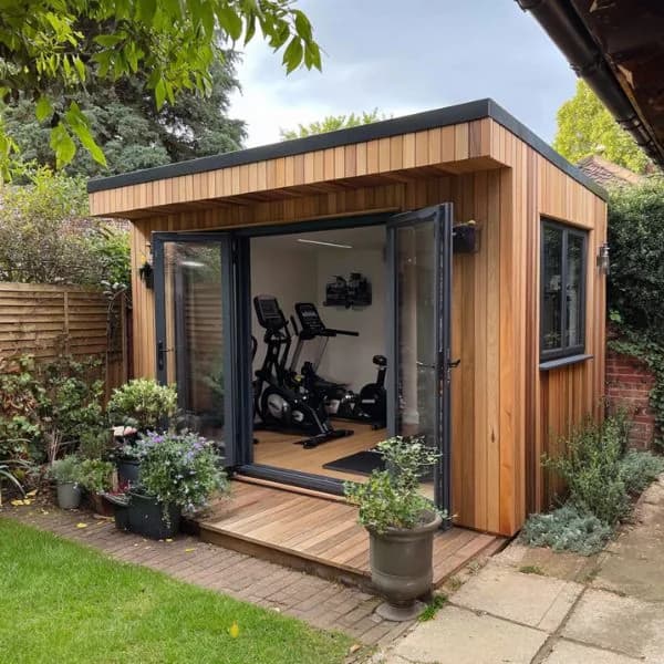 Compact timber-clad garden gym with open doors and exercise bikes