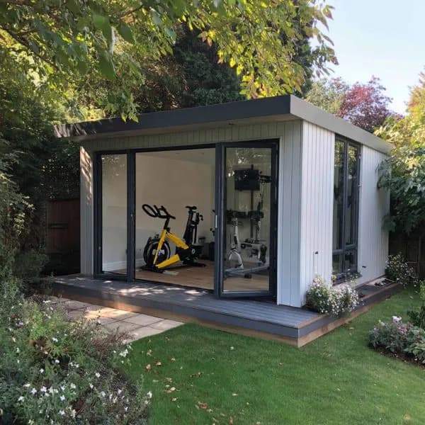 Compact light-clad garden gym with glazed doors and exercise bikes