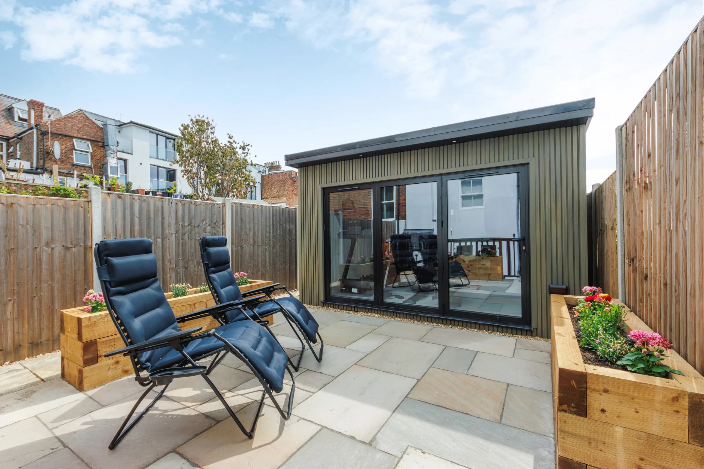 Garden gym across a paved courtyard with two reclining chairs in front