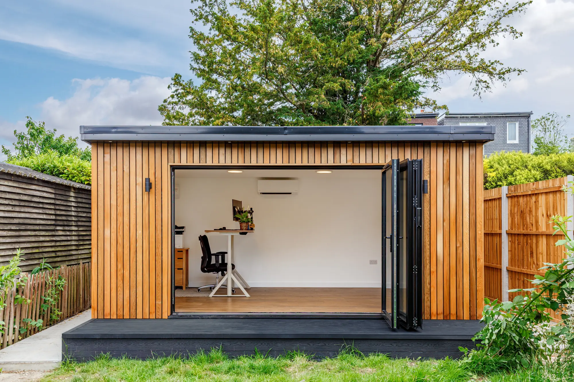 Garden office with folded-back glazed doors and a single desk