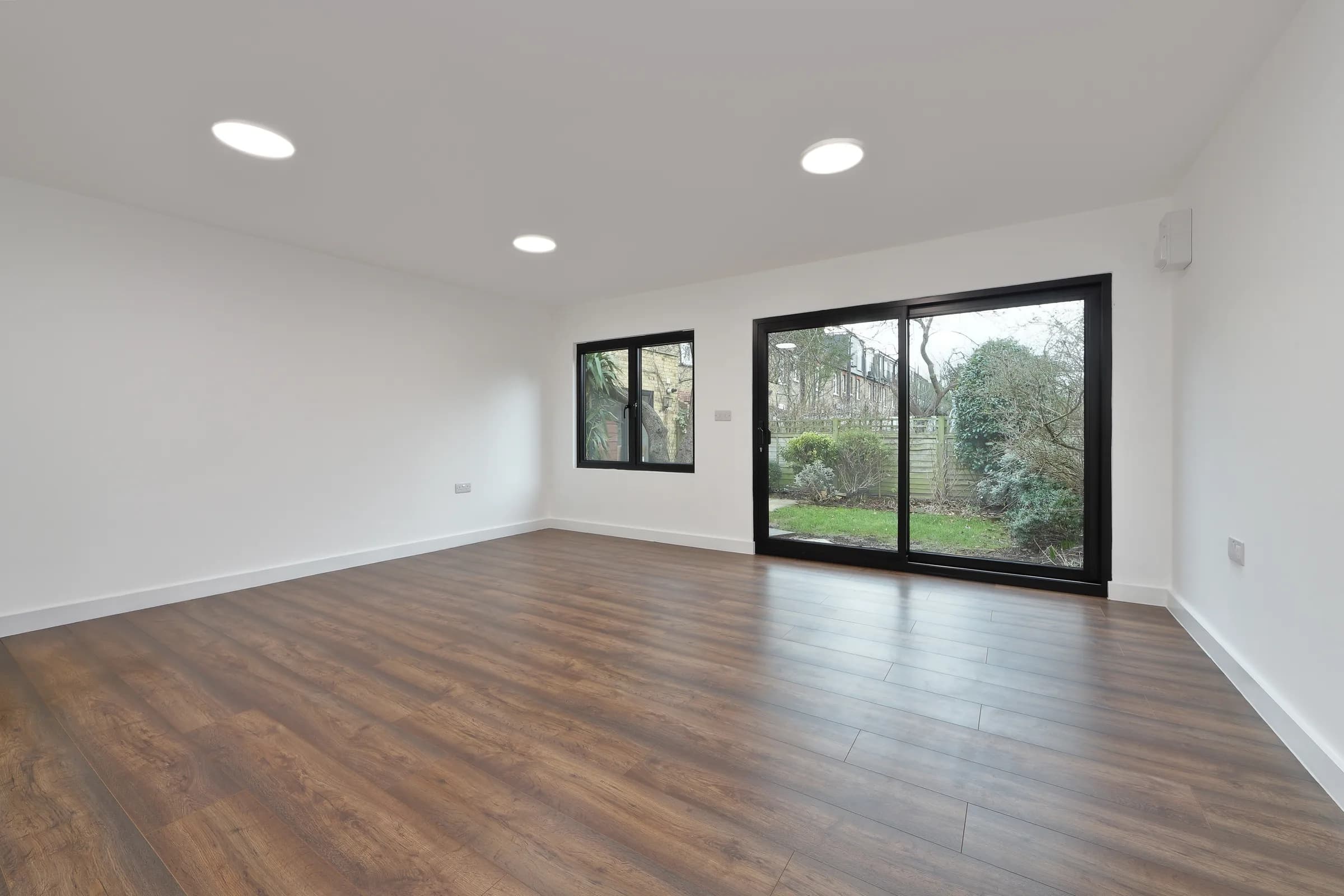 Empty garden office interior with a side window and glazed doors to the garden