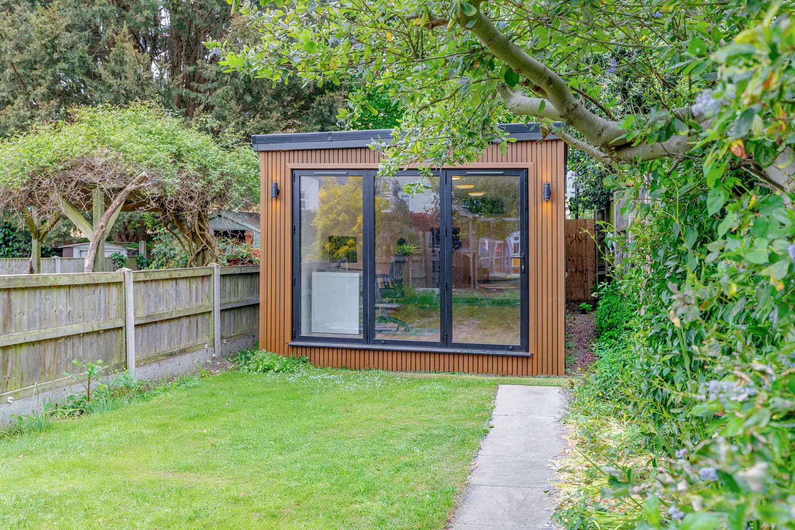 Timber-clad garden room with closed glazed doors at the end of a lawn