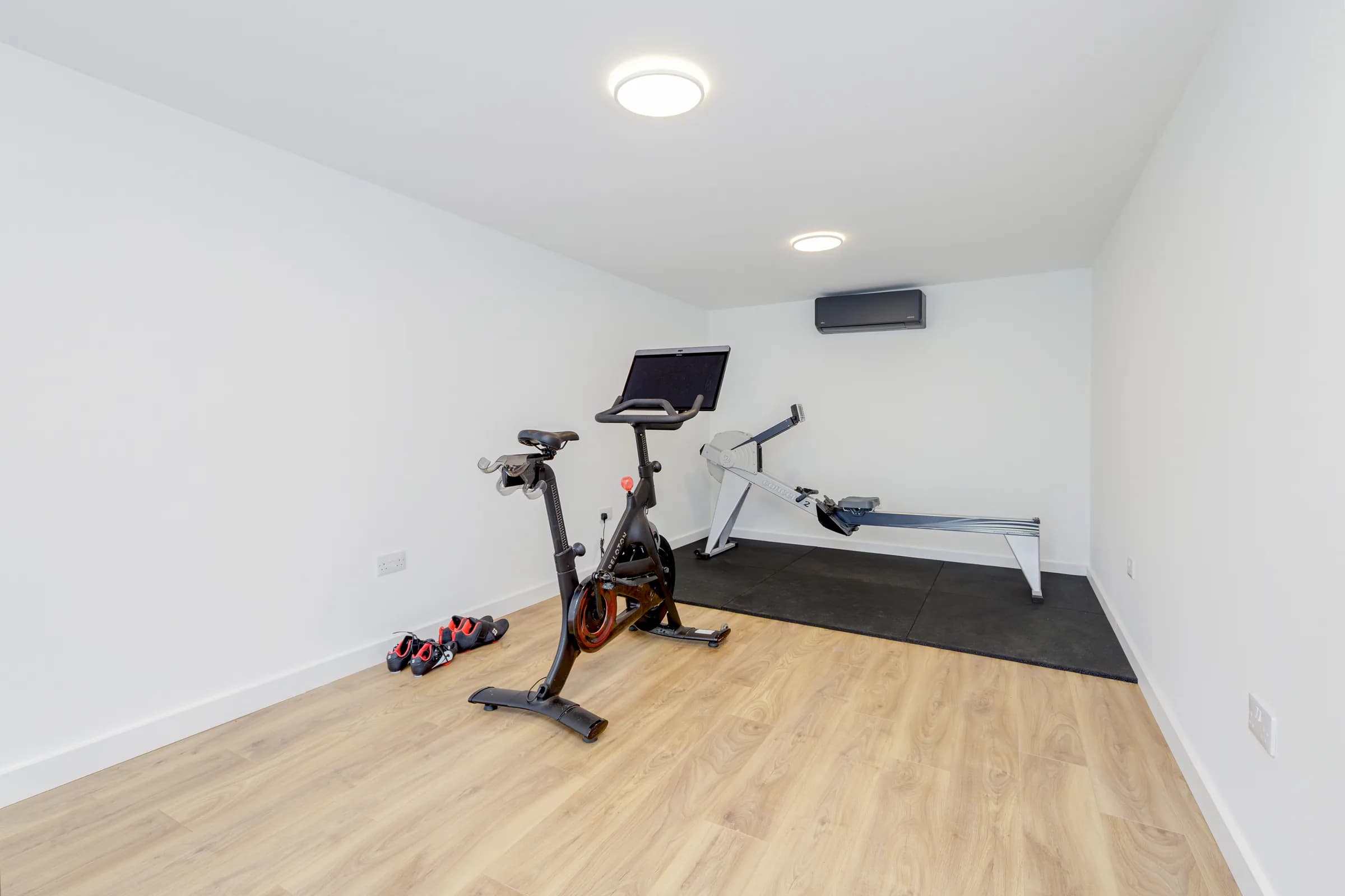 Garden room interior with exercise bike, rowing machine and wall-mounted air conditioning