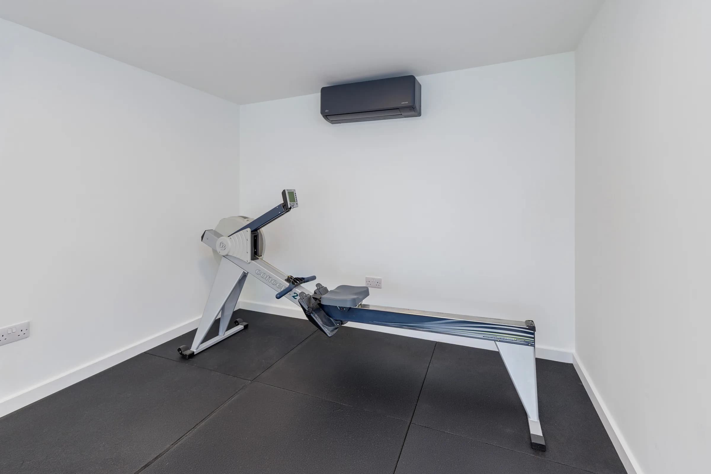 Garden studio interior with rowing machine and wall-mounted air conditioning
