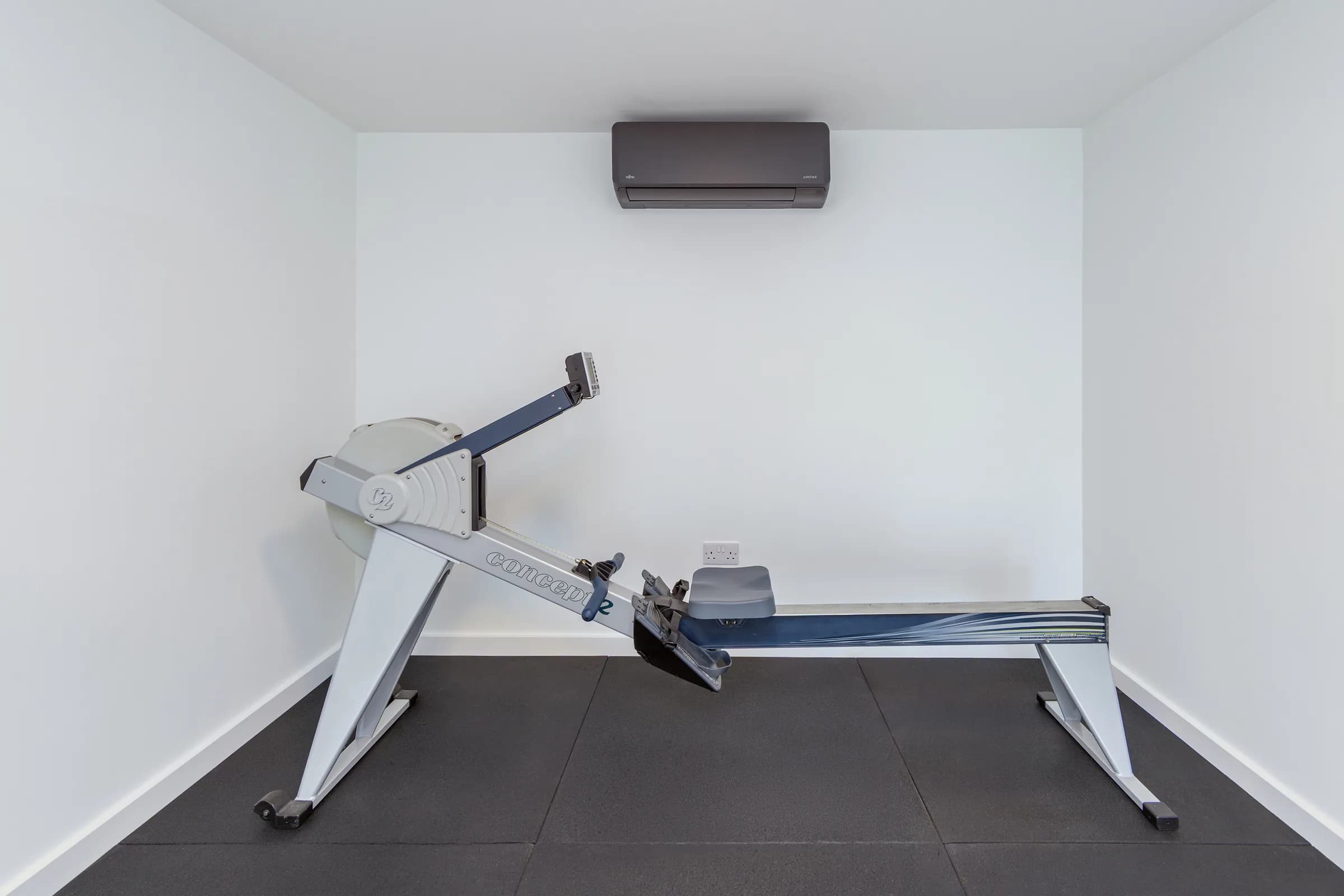 Side view of a rowing machine beneath wall-mounted air conditioning