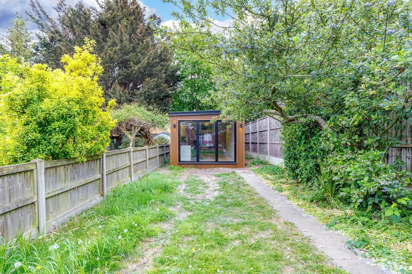 Distant view of a garden studio with closed glazed doors at the end of a lawn