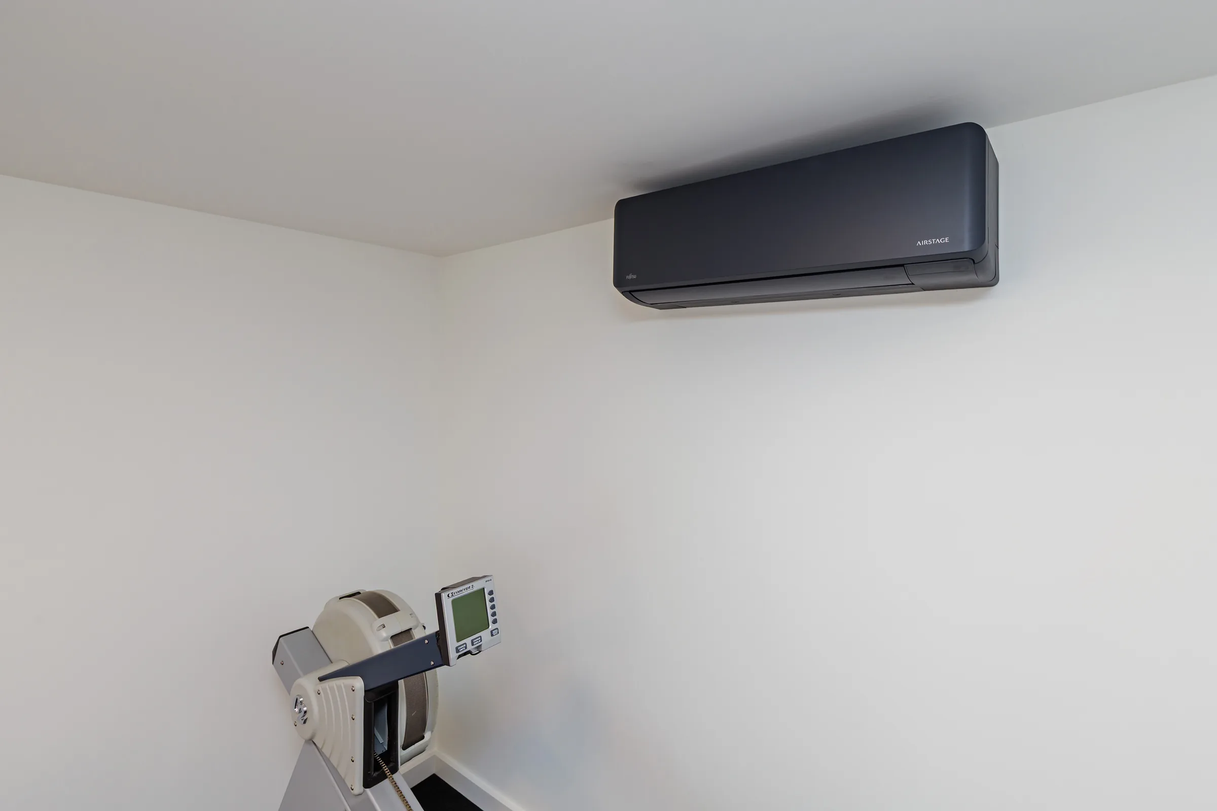 Close interior view of wall-mounted air conditioning above a rowing machine