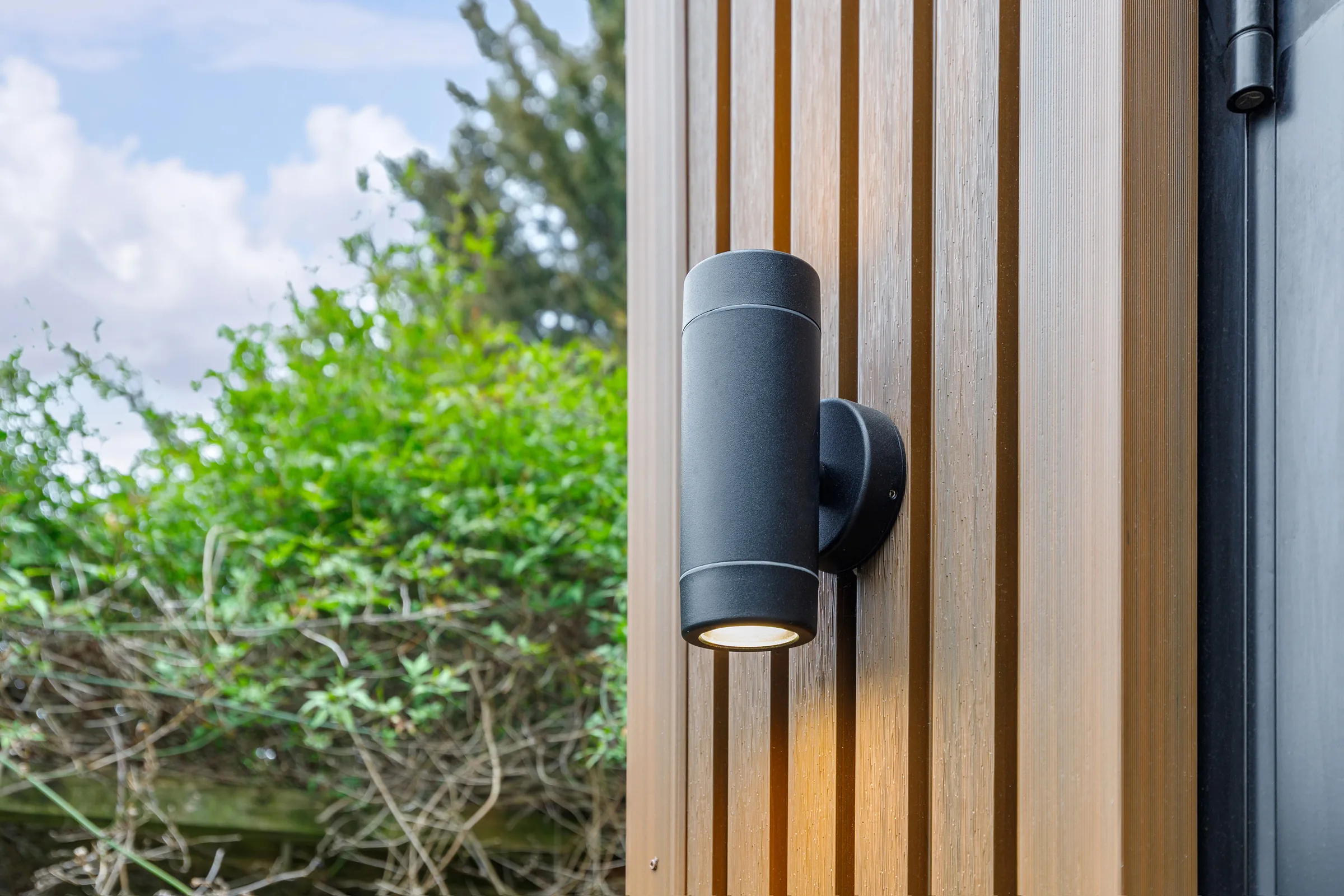Close view of a garden studio's exterior light, timber cladding and door frame