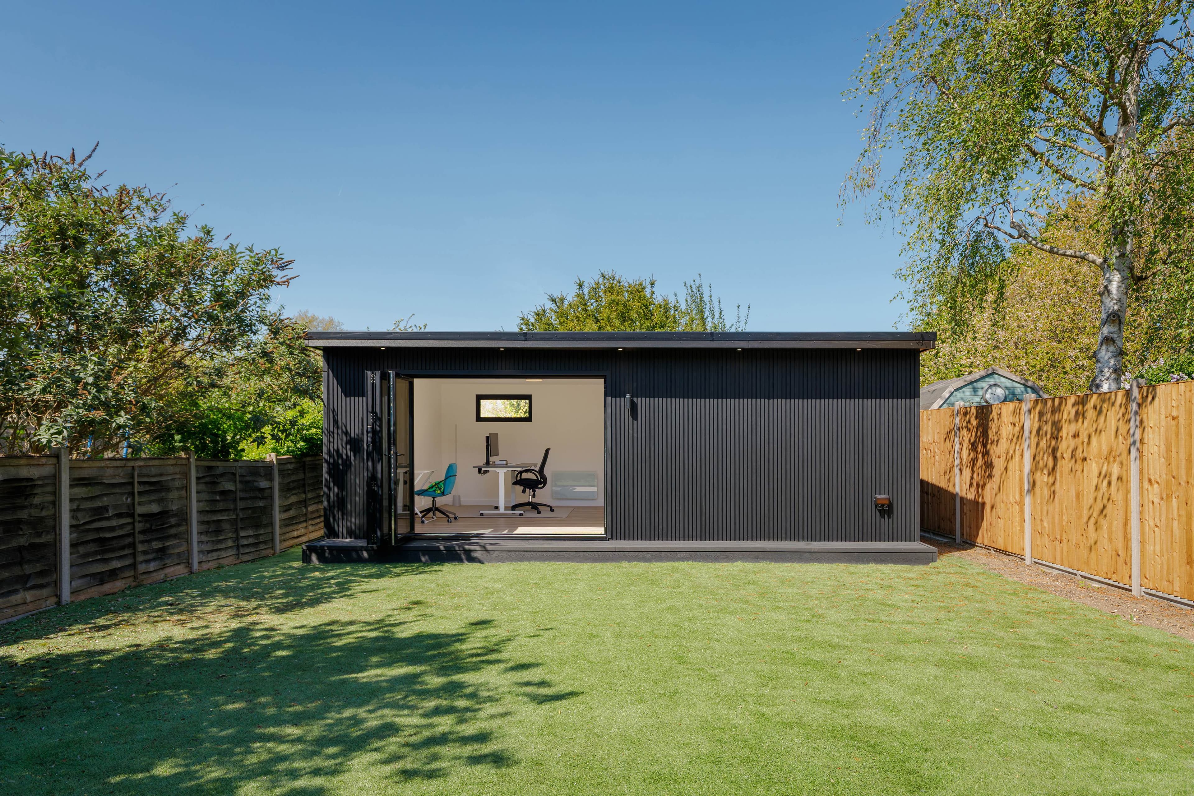 Garden office in Bedfordshire — anthracite slatted cladding with bifold doors opening onto the lawn