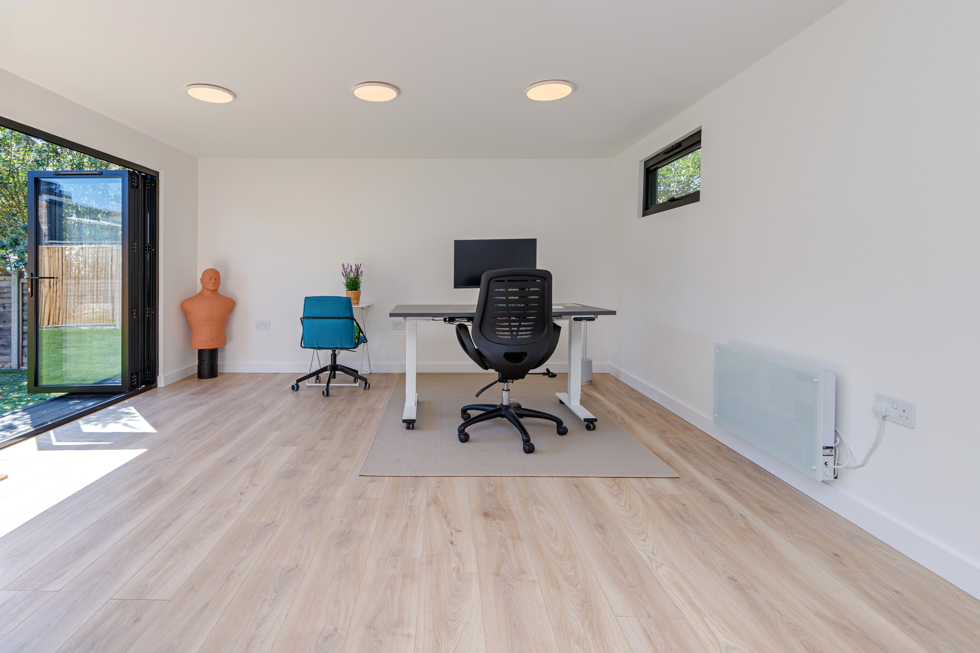 Garden office in Bedfordshire — bright interior with a sit-stand desk and bifold doors open to the garden