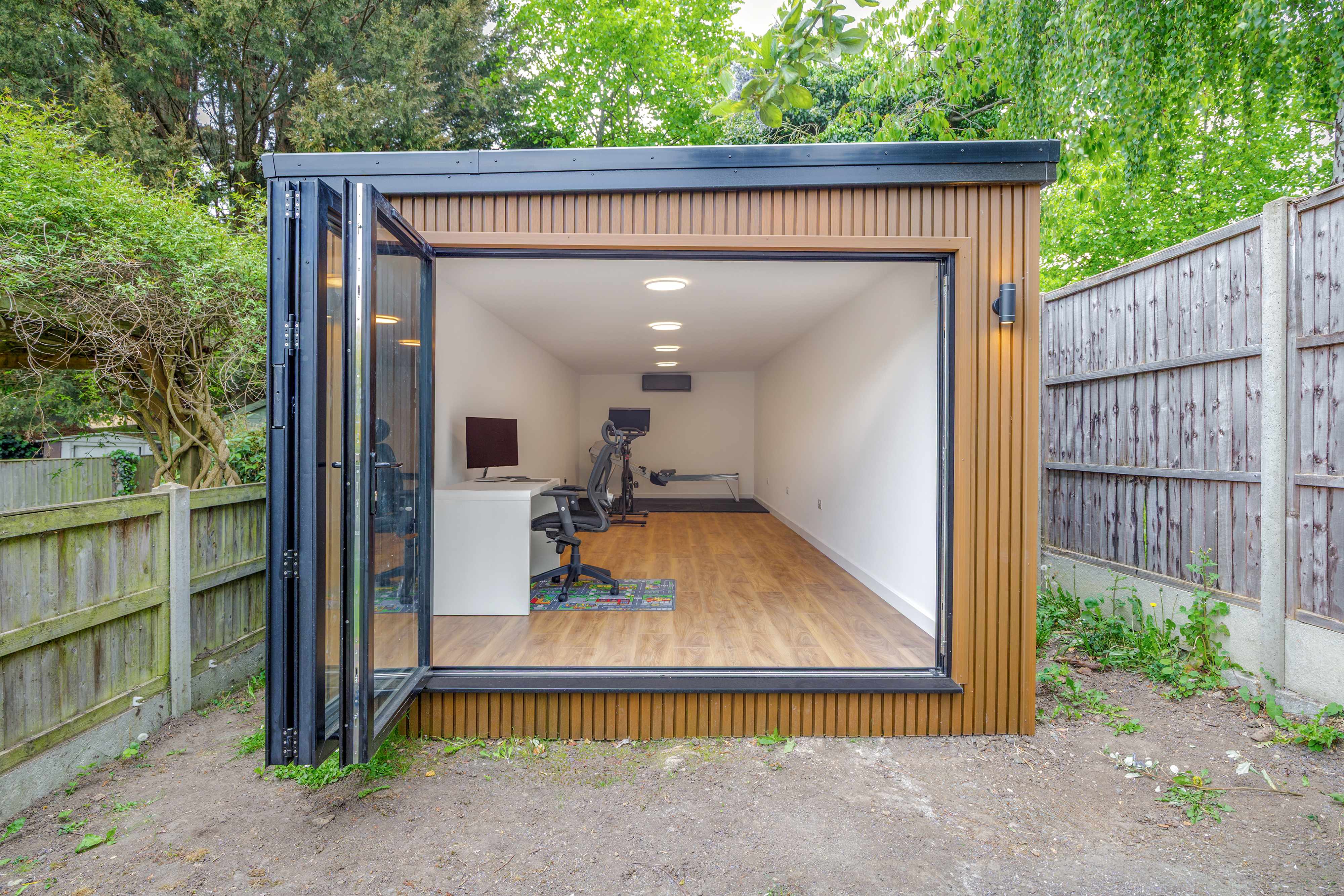 Garden office cedar-clad garden office and gym with a desk and training equipment, of the kind Beds Garden Rooms builds for Bedfordshire homes