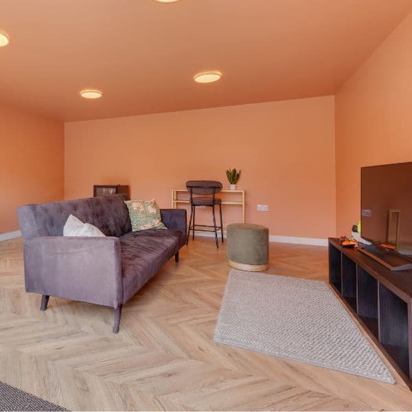 Garden office warm interior with a sofa, herringbone floor and terracotta walls, of the kind Beds Garden Rooms builds for Bedfordshire homes